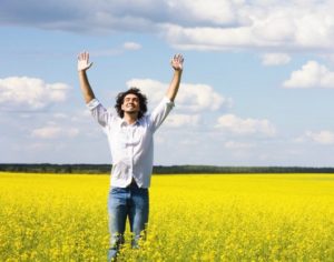 man with hands in air in spacious field