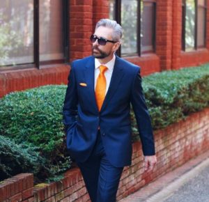 man walking down street in bright orange tie